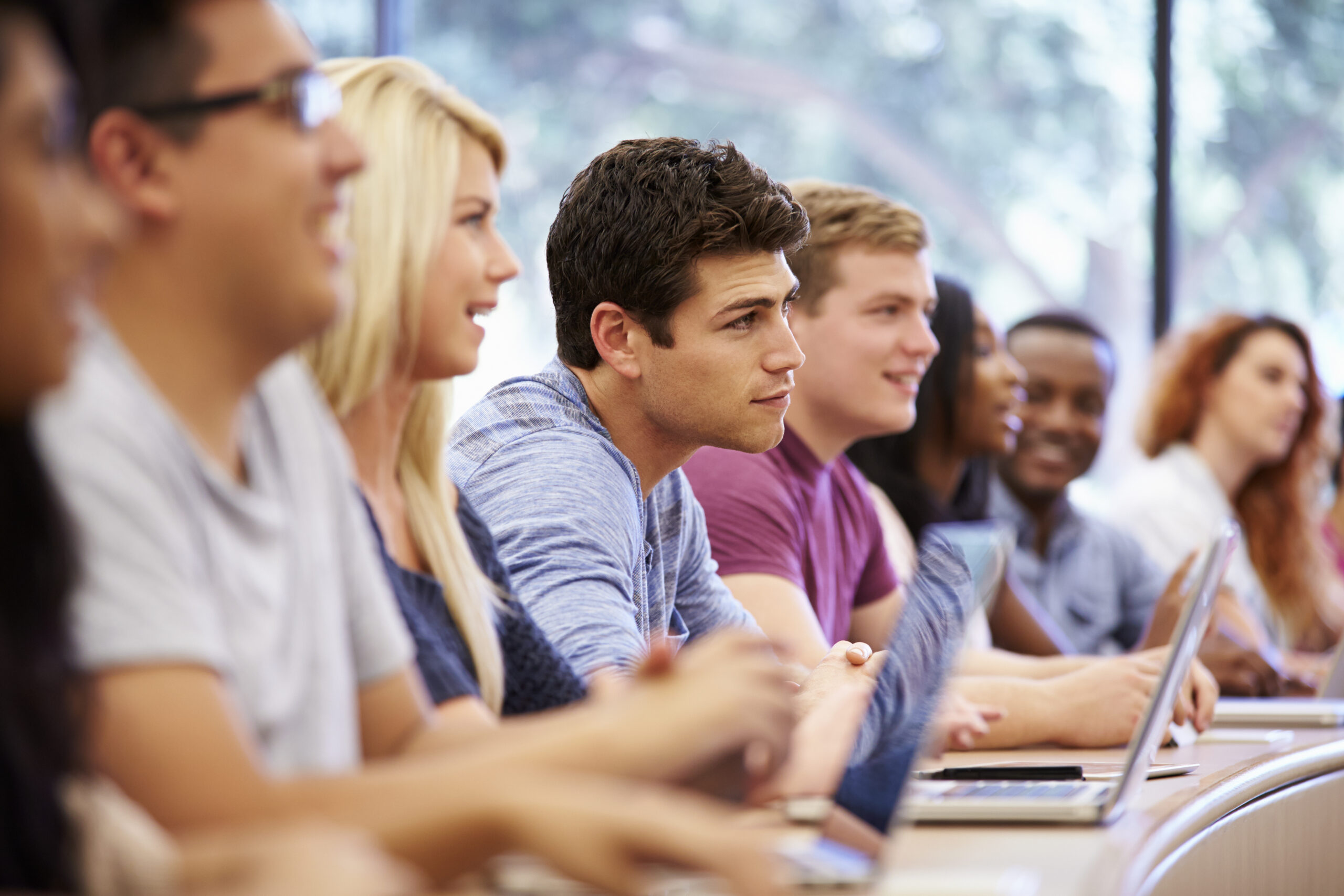 Grupo de estudiantes jóvenes atentos en clase evaluando entre un curso corto y un programa de especialización